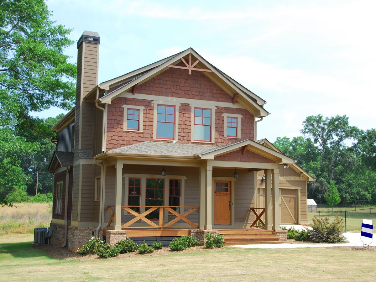 Farmhouse with a covered porch and open field behind it